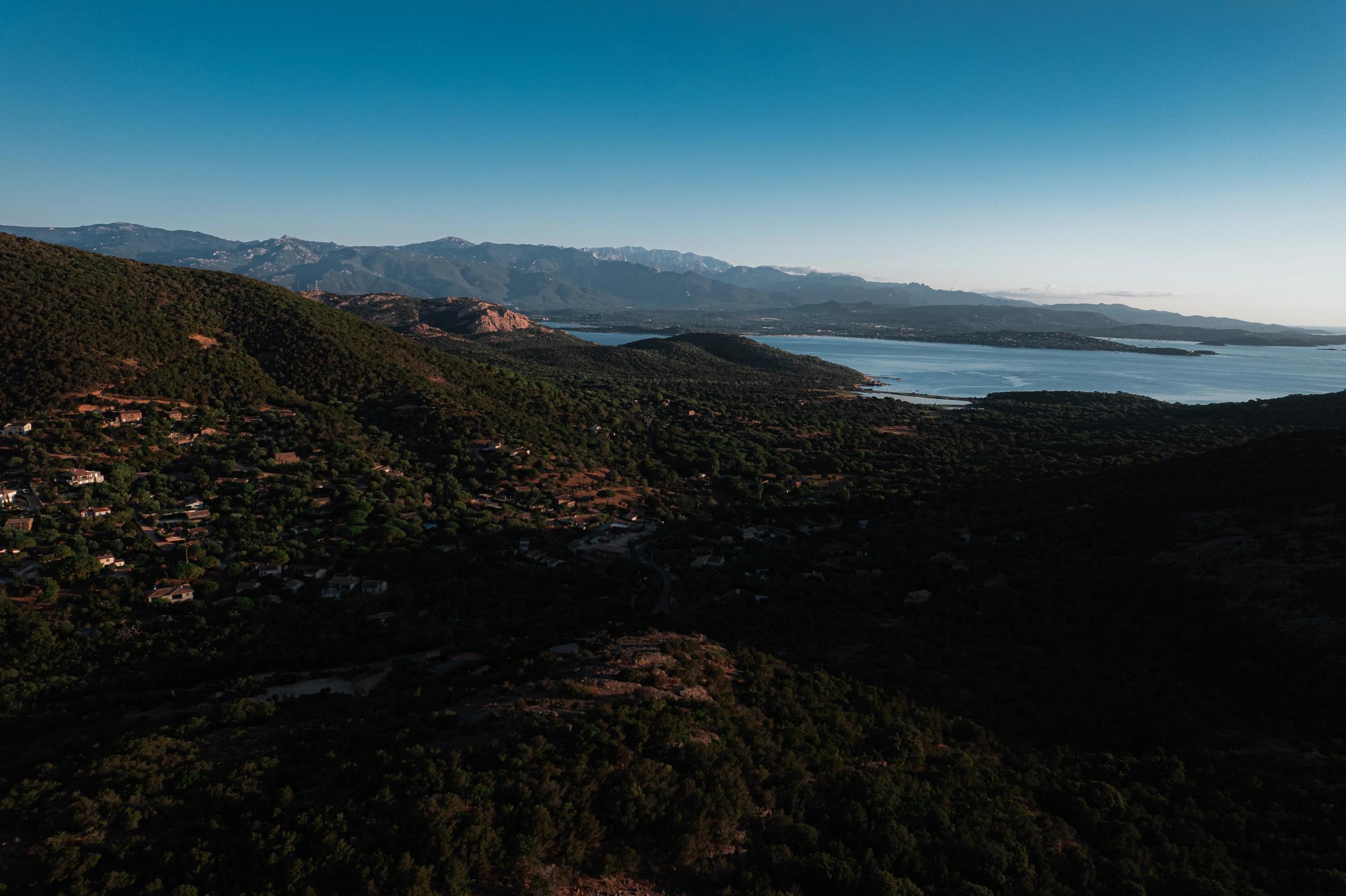 Vue de drone d'une vallée avec la mer au loin aux alentours des oliviers de Palombaggia en Corse-du-Sud.
